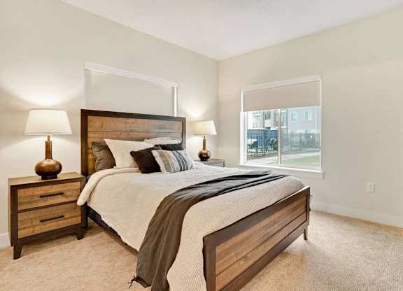 A bedroom with a large bed, two lamps, and a nightstand.