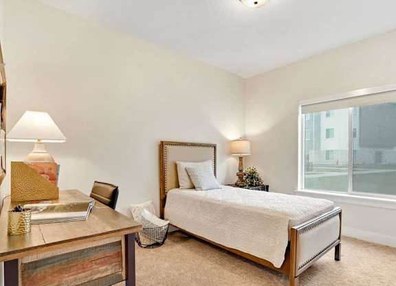 A bedroom with a bed, nightstand, and window.