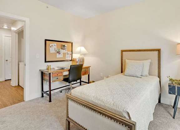 A bedroom with a bed, desk, and chair.