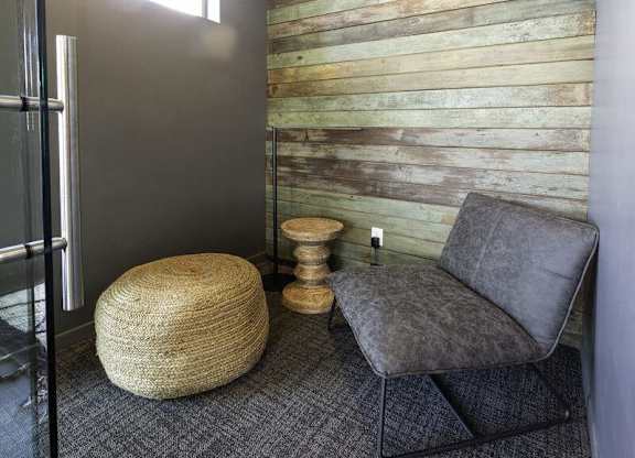 A grey chair sits in front of a wooden wall.