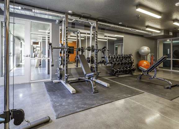 A gym with a variety of equipment including weights and weight machines.
