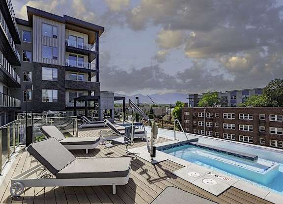 A modern apartment complex with a pool and sun loungers.