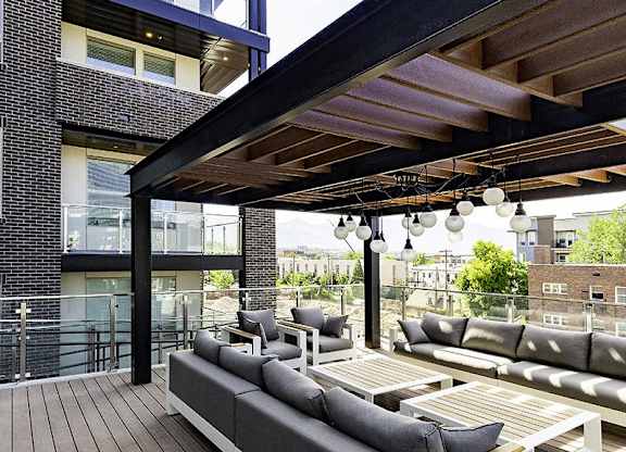 A wooden deck with a grey couch and a black pole.