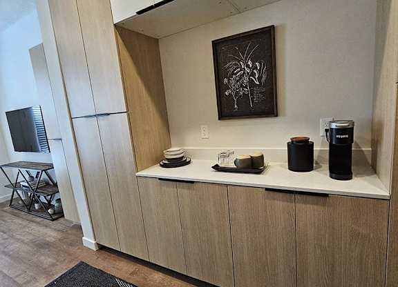 A kitchen area with a wooden cabinet and a framed picture on the wall.
