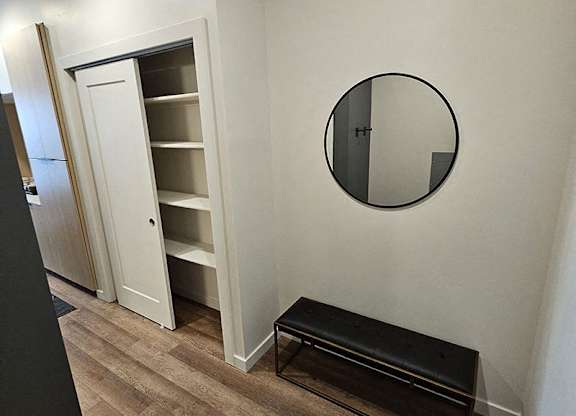 A white closet with a mirror and a bench.