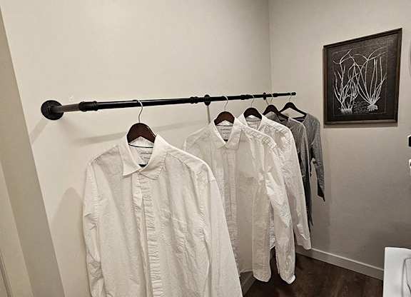 A row of white shirts hanging on a rack in a room.