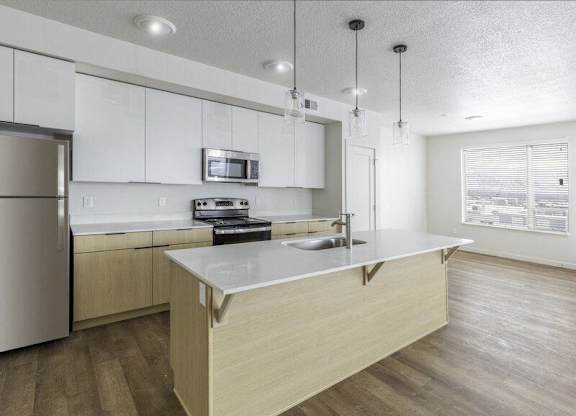 A kitchen with a refrigerator, microwave, oven, and sink.