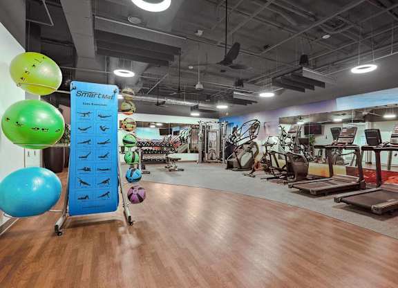 A gym with a variety of equipment and exercise balls.