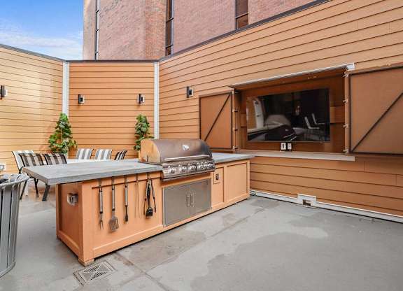 A wooden outdoor kitchen with a grill and sink.