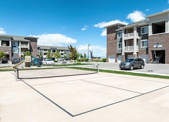 A tennis court is located in front of apartment buildings.