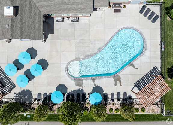 An aerial view of a pool surrounded by chairs and umbrellas.
