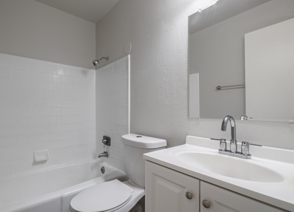 A white bathroom with a toilet, sink, and bathtub.