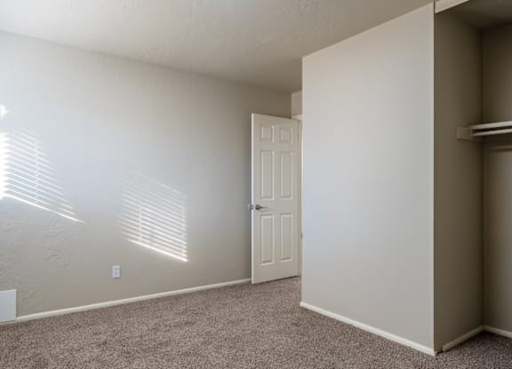 A room with a door and a window with blinds.