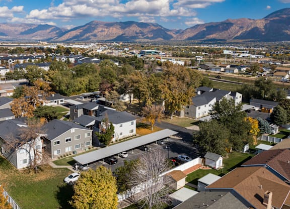 A suburban neighborhood with houses and trees in the foreground and mountains in the background.