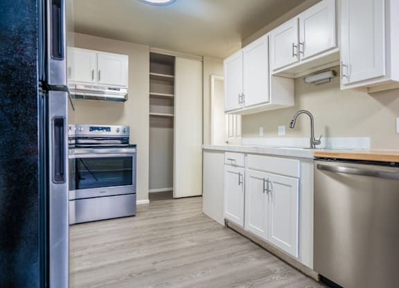 A modern kitchen with white cabinets and stainless steel appliances.