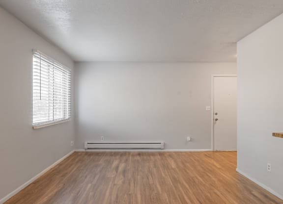 A room with wooden floors and a window with blinds.
