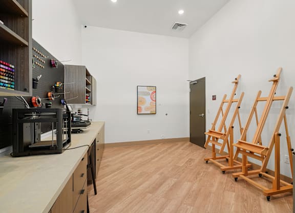A room with a white wall and a wooden floor with three wooden easels.