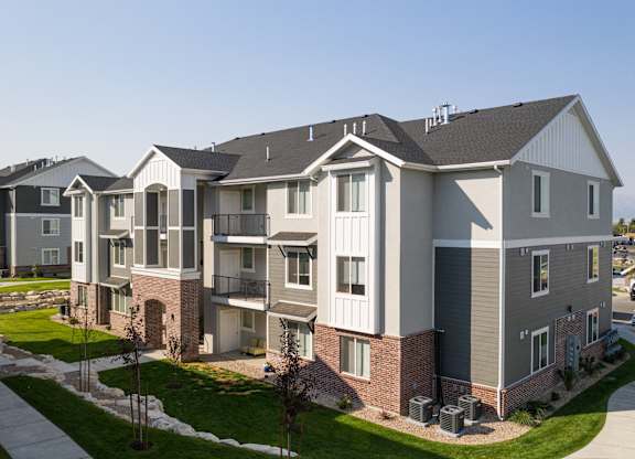 A large, modern apartment building with a well-maintained lawn in front.