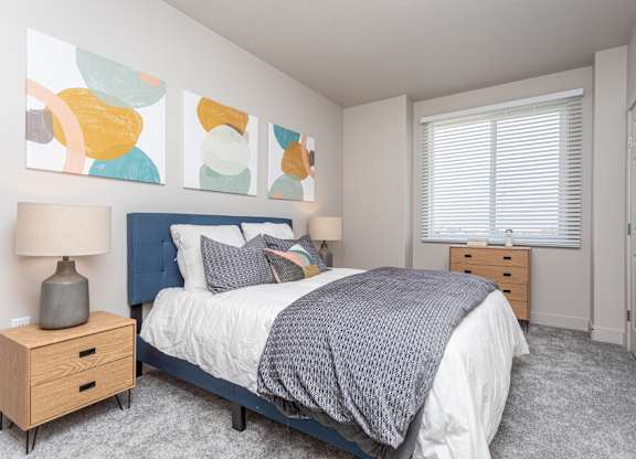 A bedroom with a bed, nightstand, and a painting on the wall.