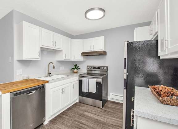 A modern kitchen with white cabinets and a wooden countertop.
