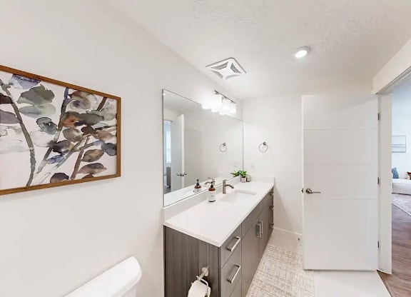 A bathroom with a white sink and a large mirror.