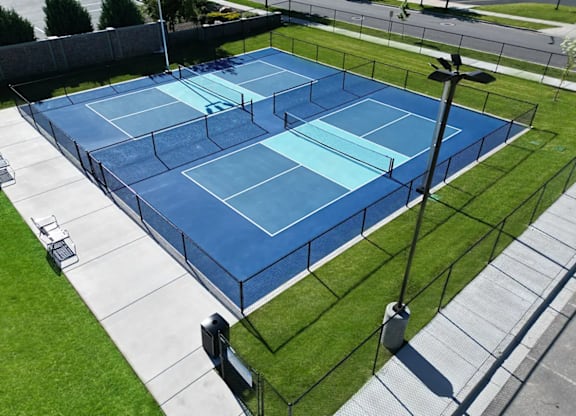 A tennis court with a blue surface and a black fence.