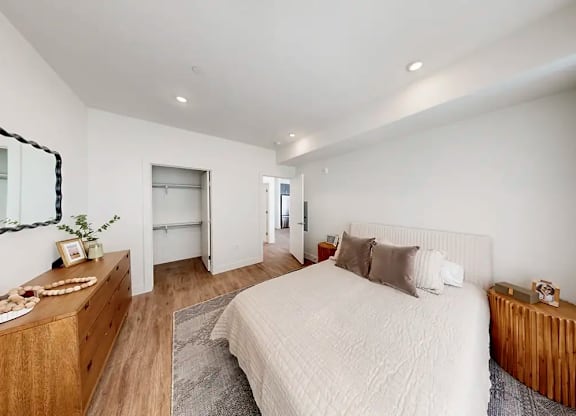 A bedroom with a large bed and a wooden dresser.