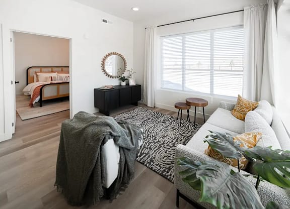 A bedroom with a bed, a bench, a couch, and a mirror.