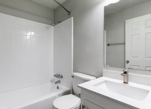 A white bathroom with a tub, toilet, and sink.