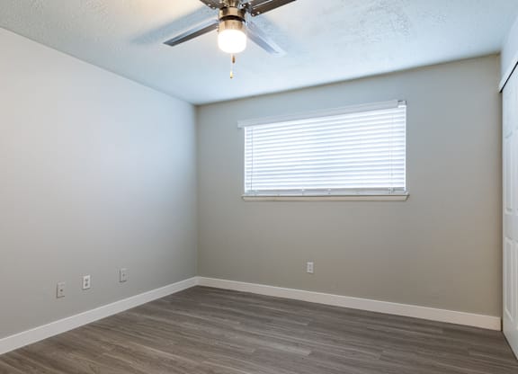 A room with a ceiling fan and a window with blinds.