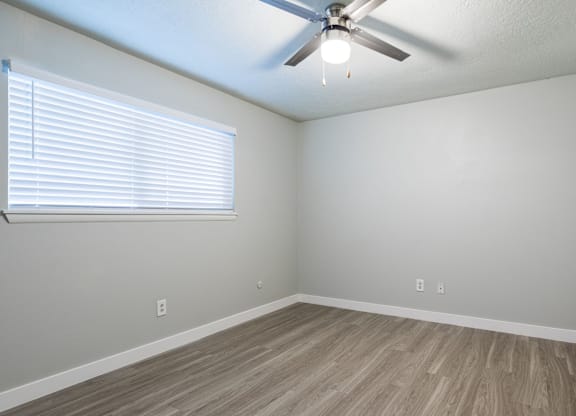 A room with a ceiling fan and a window with blinds.