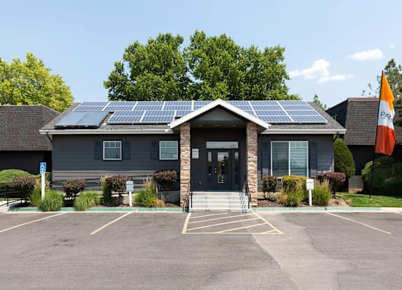 A building with solar panels on the roof and flags on the front.