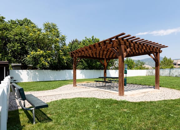 A wooden pergola is situated in a grassy area.