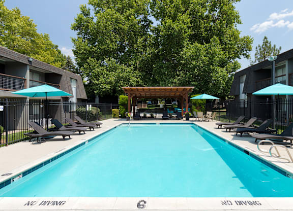 A large swimming pool surrounded by lounge chairs and umbrellas.