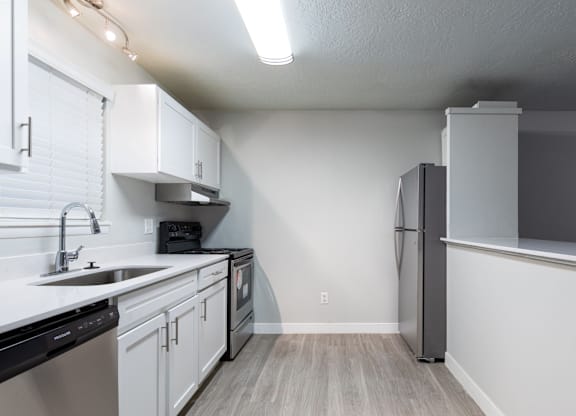 A kitchen with white cabinets and a black dishwasher.