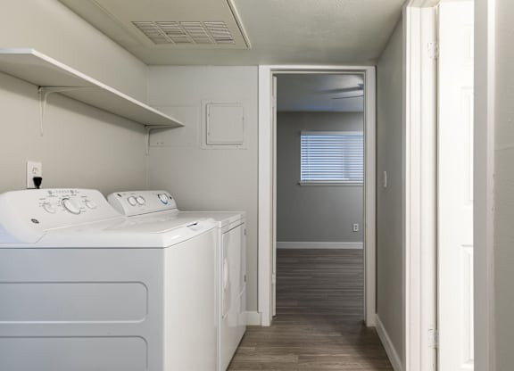 A white washing machine in a small room with a door open to a hallway.