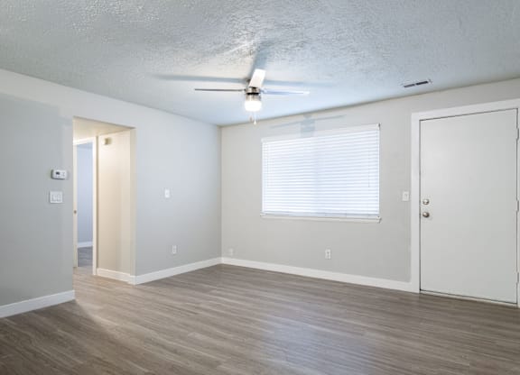A room with a ceiling fan and wooden flooring.