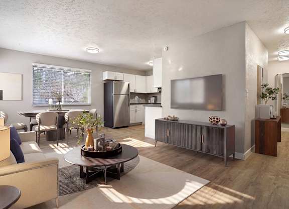 A modern living room with a large window, a flat screen TV, and a kitchen area in the background.