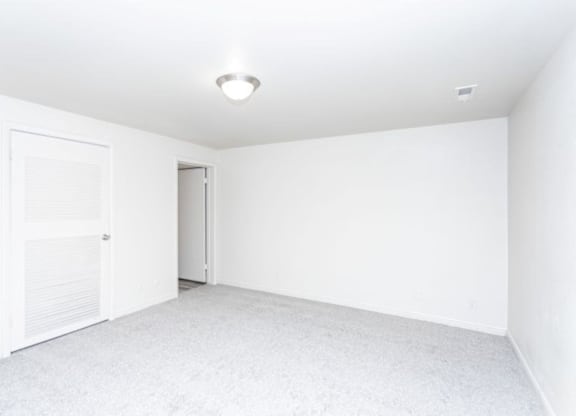 A white room with a door and a light on the ceiling.