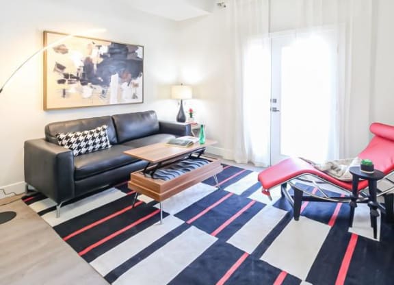 a living room with a black couch and a rug