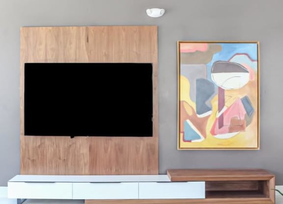 a living room with a tv and a painting on the wall