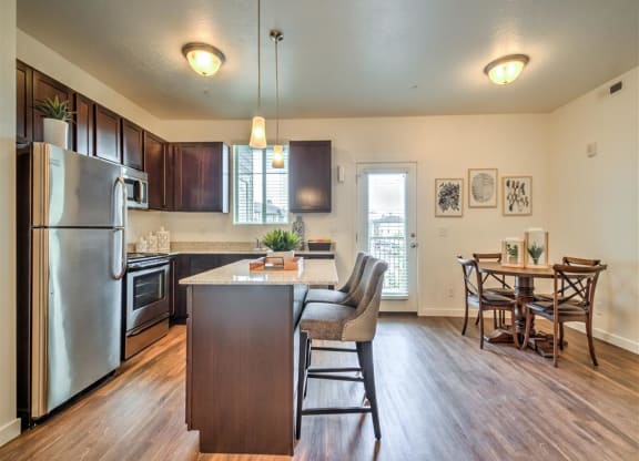 a kitchen with a large island and a stainless steel refrigerator at Aderra apartments for rent in Roy, Utah