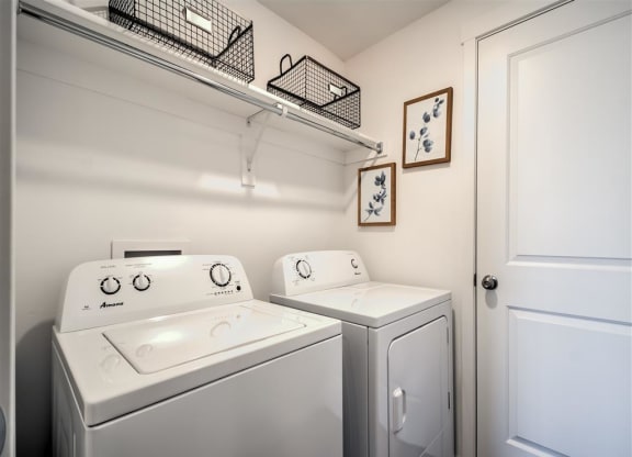 a white laundry room with two washes and a dryer at Aderra apartment complex in Roy, Utah