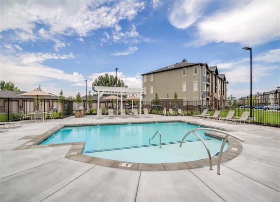 a swimming pool with an Aderra apartment building in the background in Roy, Utah