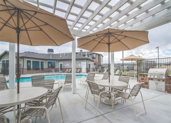 a large patio with tables and chairs and a swimming pool at Aderra apartments in Roy, Utah