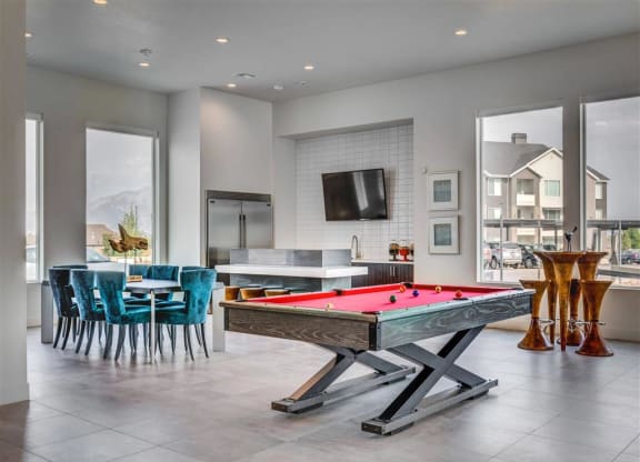 a pool table in a living room with a kitchen  at Affinity 56 Apartments in West Jordan, Utah