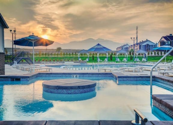 a swimming pool at sunset with mountains in the background  at Affinity 56 Apartments in West Jordan, Utah