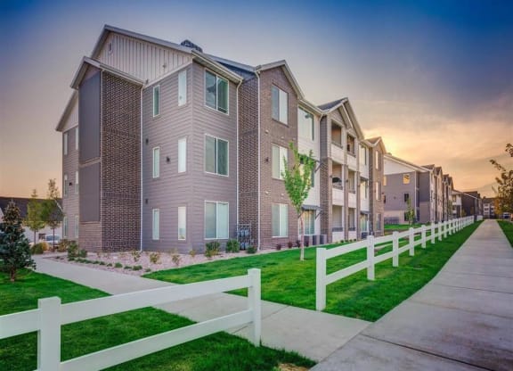 a row of town homes with a sidewalk and white fence  at Affinity 56 Apartments in West Jordan, Utah
