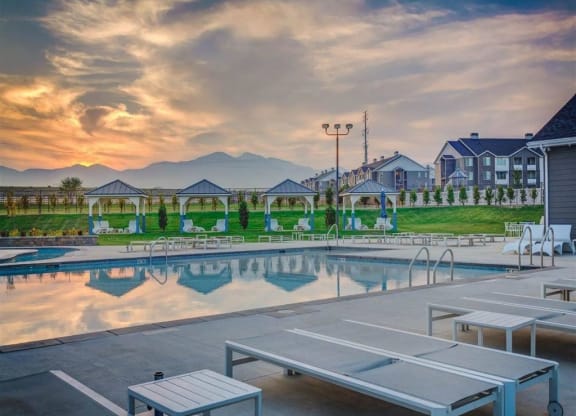 a swimming pool at sunset with houses and mountains in the background  at Affinity 56 Apartments in West Jordan, Utah