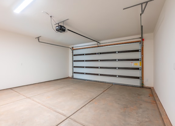 A white room with a grey floor and a grey wall with a shelf and a light on the wall.